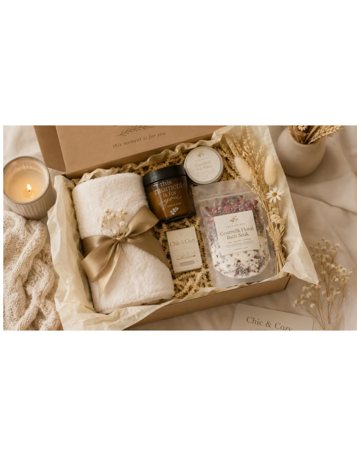 Serenity Spa Gift Set with cream towel tied with taupe ribbon, goat milk floral bath soak, amber jar, round tin and small box.